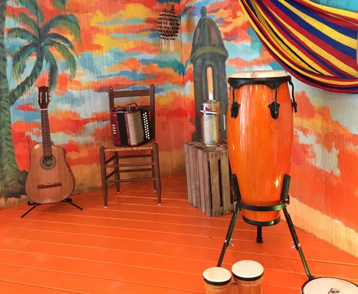 Musical instruments displayed against a mural of a Cuban sunset