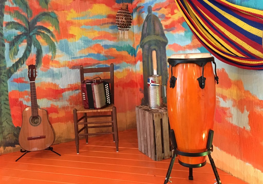 Musical instruments displayed against a mural of a Cuban sunset